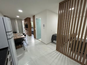 A modern kitchen with a refrigerator, a dining table set for four, and a wooden partition.