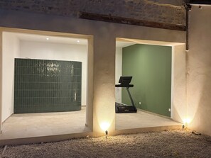 A room with a tiled wall, a treadmill, and a green wall.