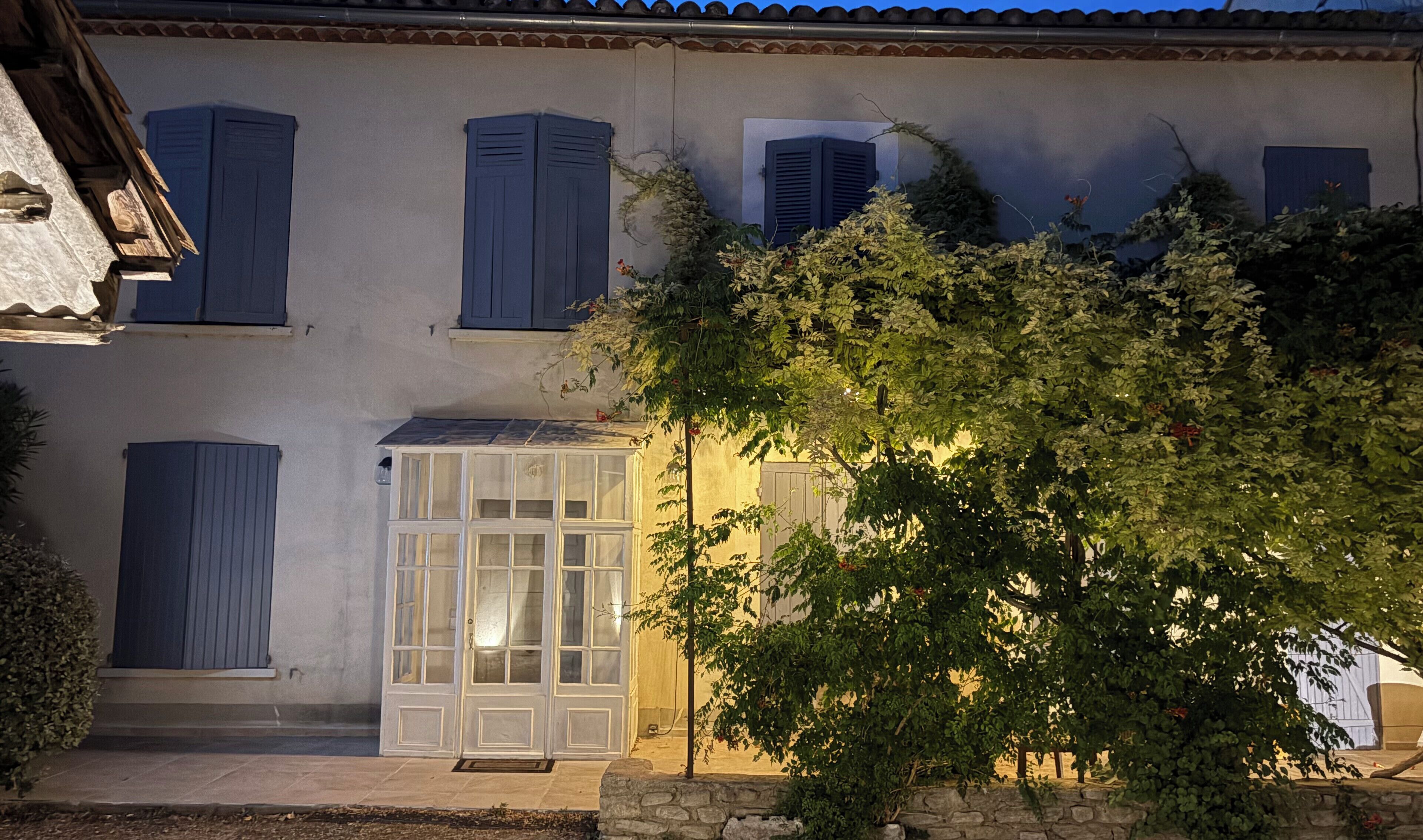 Un edificio con varias ventanas, una puerta y una estructura pequeña con paneles de vidrio.