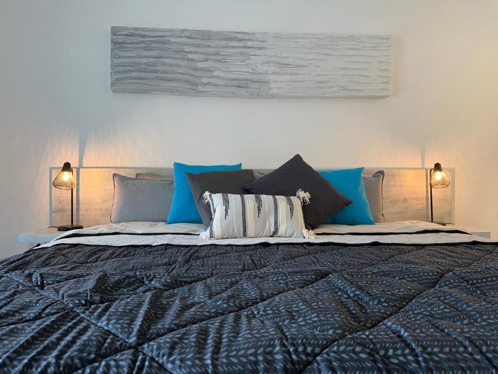 A bed with a patterned quilt, two bedside lamps, and a wall-mounted artwork.
