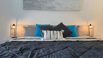 Un letto con una coperta a motivi, due lampade da comodino e un'opera d'arte appesa al muro.