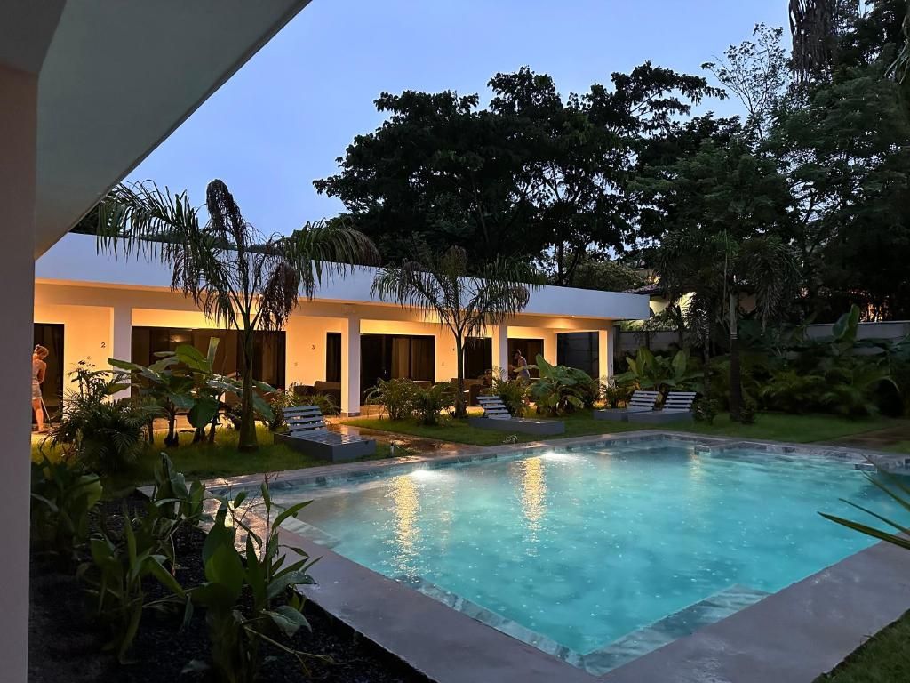 Un edificio moderno con piscina, rodeado de vegetación exuberante y árboles.