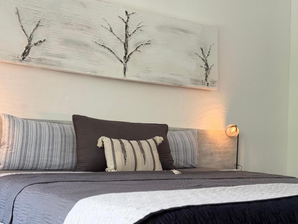 A bedroom with a bed, pillows, a bedside lamp, and a wall painting.