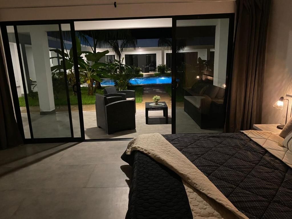 A bedroom with a bed, a view of a swimming pool, and a patio area with outdoor furniture.