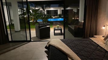 Un dormitorio con cama, vistas a una piscina y un patio amueblado.