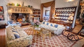 A cozy living room with a fireplace, patterned sofas, a wooden coffee table, and a wall of clocks. - Spedlins Castle – A Magical Escape in the Scottish Countryside (Templand)