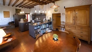 A rustic kitchen with wooden beams, a round dining table, and a bookshelf filled with books. - Spedlins Castle – A Magical Escape in the Scottish Countryside (Templand)
