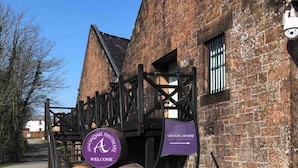 A brick building with a wooden gate and signs indicating the visitor center and welcome area. - Spedlins Castle – A Magical Escape in the Scottish Countryside (Templand)