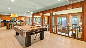 A pool table in a room with wooden walls and a balcony with a view.