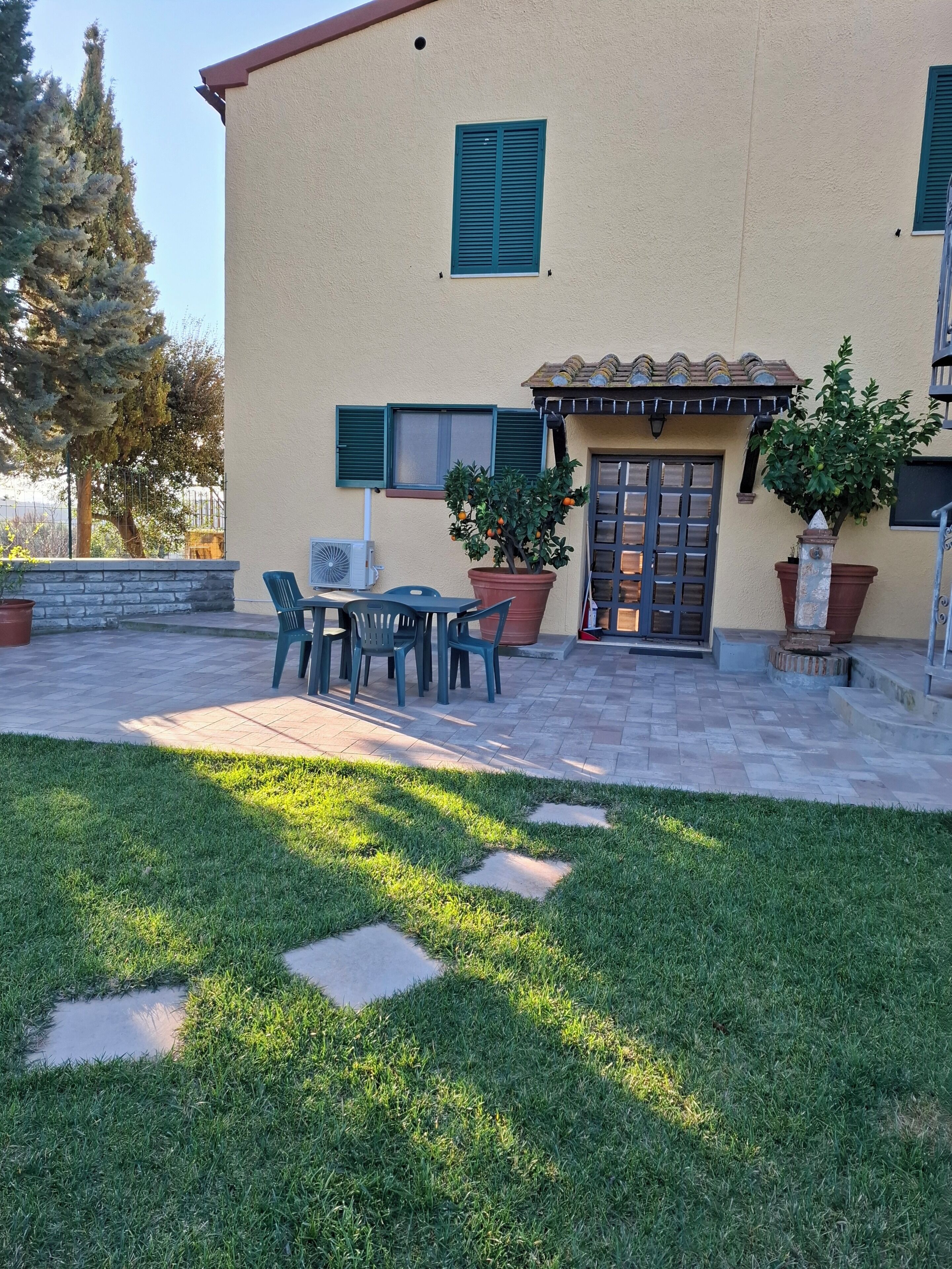 Un edificio con un patio, mobiliario exterior y plantas en macetas.
