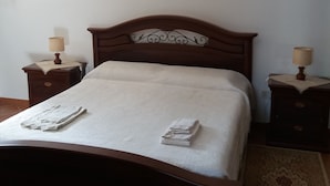 A bedroom with a large bed, two nightstands, a painting above the bed, and a patterned rug on the floor.