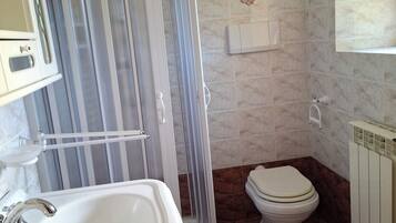 Un bagno con cabina doccia, lavandino, water e termosifone.