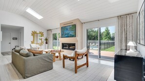 Amplia sala de estar con chimenea, un cuadro grande y vistas al jardín trasero.