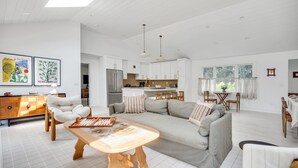 Amplia sala de estar con sofá, mesa de centro de madera y una cocina al fondo.