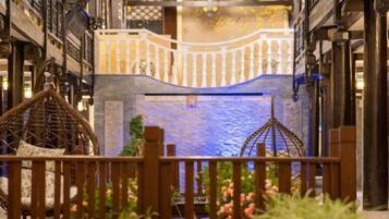 A narrow corridor with a decorative railing, a hanging chair, and a small water feature.