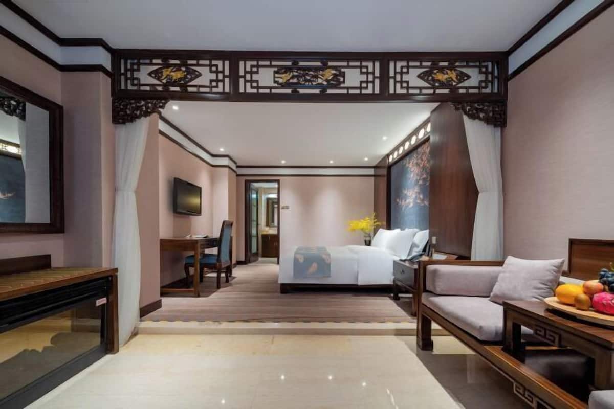 A hotel room with a bed, a sofa, a desk, and a TV.