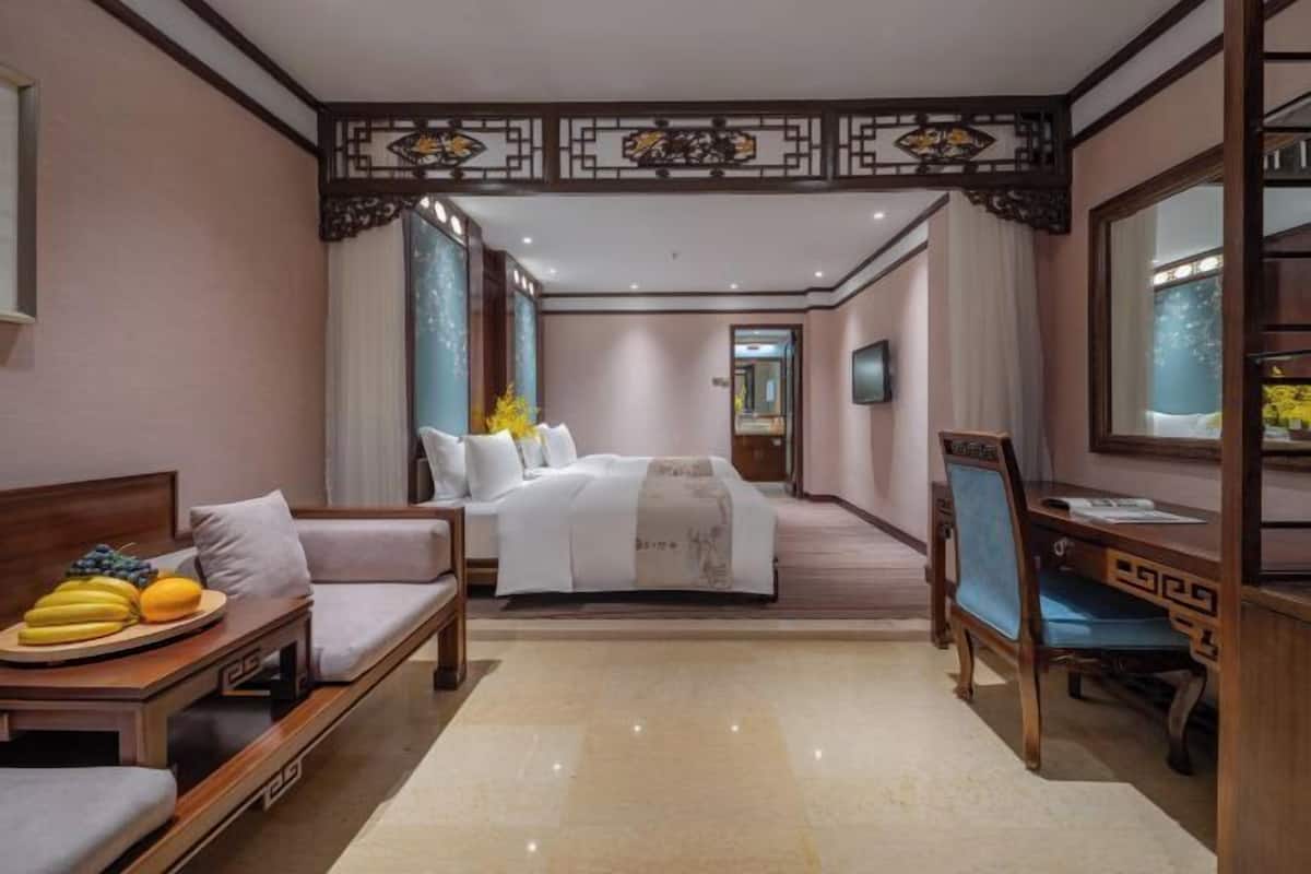 A hotel room with a bed, a desk, a chair, a TV, and a window.
