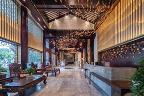 A hotel lobby with a long corridor, wooden furniture, and a reception desk. - DuoFu Resort (Lijiang Ancient City South Gate) (Lijiang)