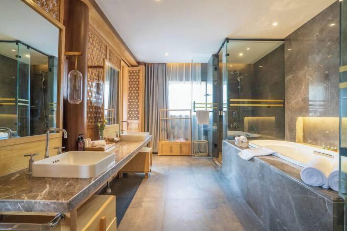 A modern bathroom with two sinks, a bathtub, and a glass-enclosed shower.