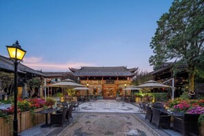 A traditional building with a tiled roof and a courtyard with tables and chairs. - DuoFu Resort (Lijiang Ancient City South Gate) (Lijiang)