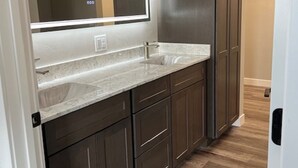 Une cuisine moderne avec des meubles de couleur sombre, un plan de travail en marbre et un grand miroir au-dessus de l’évier.