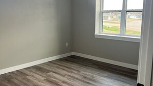 Une pièce dotée d’une grande fenêtre, de murs gris et d’un plancher en bois.