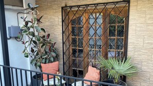 Un balcon avec des sièges d’extérieur, une piscine et un mur en bois avec une fenêtre.