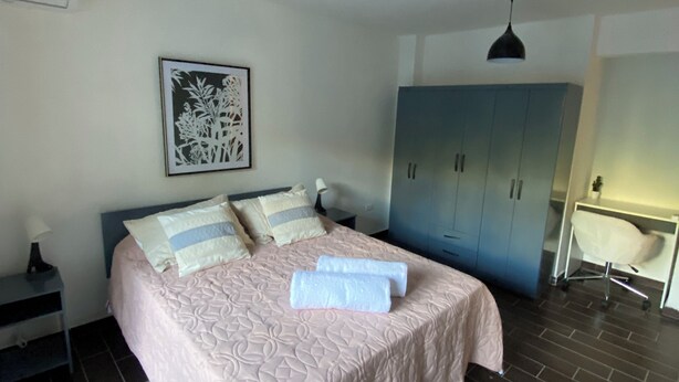 Une chambre à coucher comprenant un lit, une table de chevet, un bureau, une chaise et une armoire.