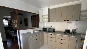 Une cuisine moderne avec des meubles blancs, un four à micro-ondes, un grille-pain et une bouilloire.