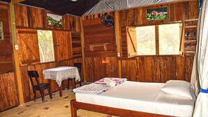 A wooden room with a bed, a table, and chairs. - Hostal Caño Nevera (La Macarena)