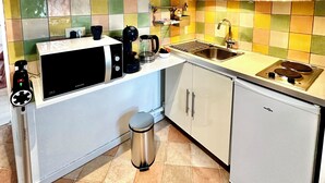 A compact kitchen with white cabinets, a microwave, a coffee maker, and a sink.