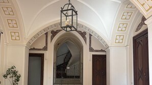 Un vaste hall d’entrée avec un sol à motifs, un lustre et un escalier menant à l’étage supérieur.