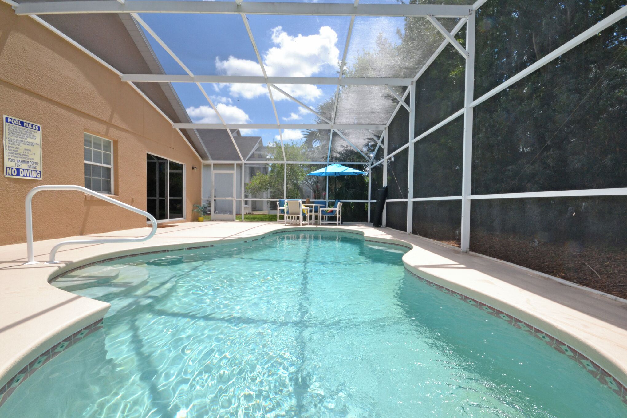 Ein Hallenbad mit Glasdach, Liegestuhl und blauem Sonnenschirm.