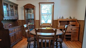 Comedor tradicional con una mesa y sillas de madera, un aparador grande de madera y una ventana con vista a árboles.