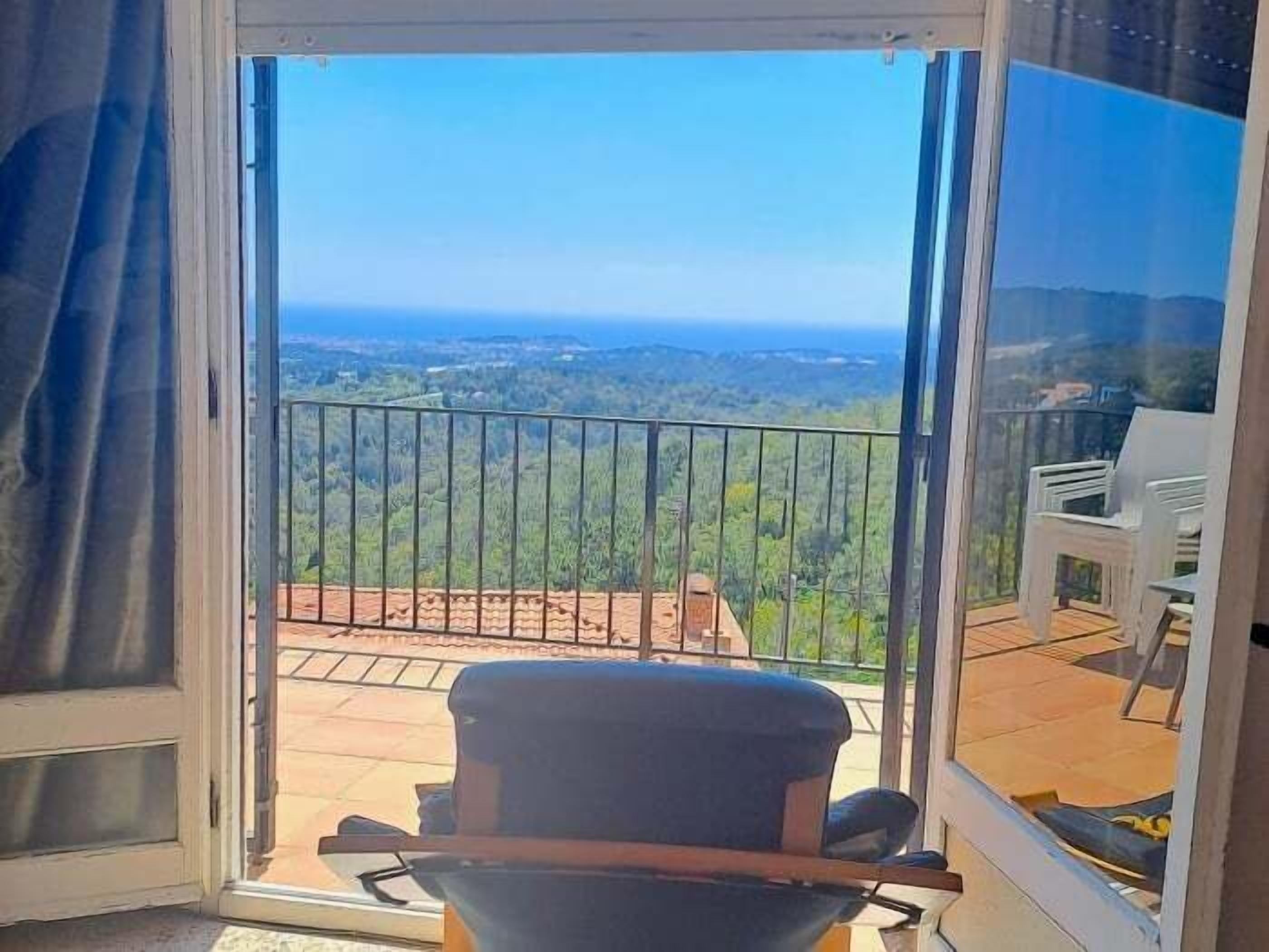 A balcony with a view of a landscape, a chair, and a table.