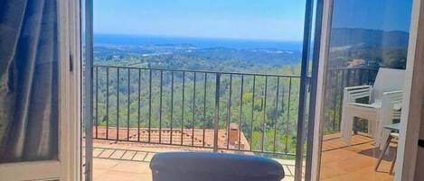 A balcony with a view of a landscape, a chair, and a table.