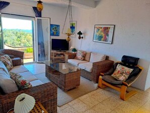 A living room with wicker furniture, a flat-screen TV, and artwork on the walls.