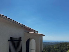 A building with a tiled roof, an arched doorway, and a view of a forested landscape.