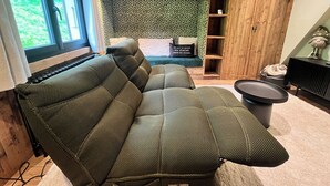 A cozy living room with a sectional sofa, a small round table, and a wooden cabinet with shelves. - Chalet le Nutshell - AravisTour (Thônes)