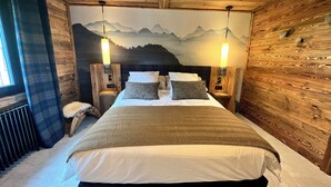 A wooden-paneled bedroom with a bed, nightstands, and a mountain mural on the wall. - Chalet le Nutshell - AravisTour (Thônes)