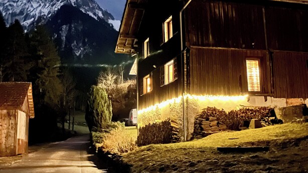 A wooden house with a sloped roof, a visible chimney, and a lit exterior. - Chalet le Nutshell - AravisTour (Thônes)