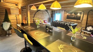 A wooden interior with a long dining table, yellow chairs, and a decorative gnome. - Chalet le Nutshell - AravisTour (Thônes)