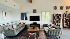 A modern living room with two grey sofas, a wooden coffee table, a TV, and a bookshelf. - Bellevue Spéra (Spéracèdes)