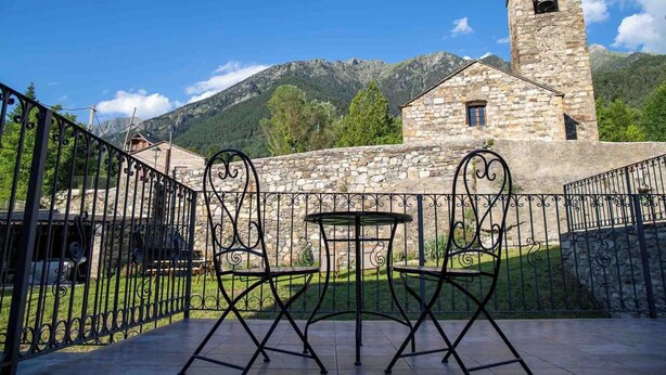 A stone building with a bell tower, surrounded by a metal fence and featuring outdoor seating. - Rural House with authentic apartments 1.340m, with garden, bbq and terrace (Senet)