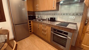 A modern kitchen with wooden cabinets, stainless steel appliances, and a tiled backsplash. - Rural House with authentic apartments 1.340m, with garden, bbq and terrace (Senet)