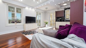 A modern living room with a flat-screen TV, a sofa, and a kitchen area with cabinets and a countertop. - Chateau Dabo (Novalja)