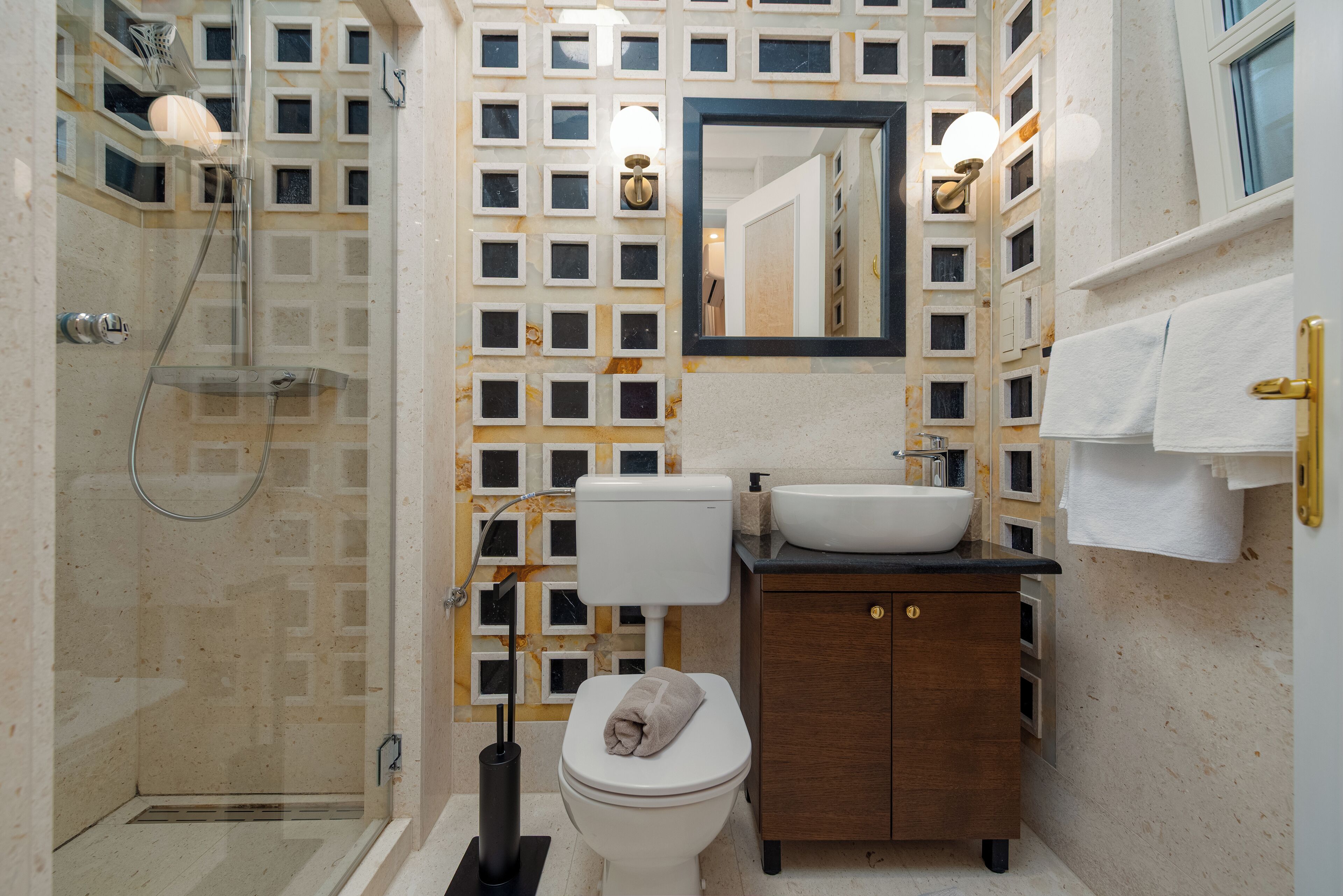 Un bagno con doccia vetrata, un WC, un lavandino e uno specchio.