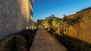 A stone pathway flanked by buildings and trees, leading towards a distant structure. - Chateau Dabo (Novalja)