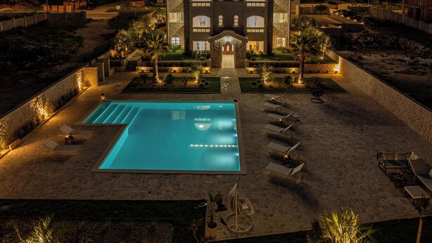 A large building with a swimming pool, sun loungers, and a well-lit garden area. - Chateau Dabo (Novalja)
