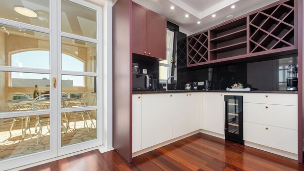 A modern kitchen with white cabinets, a black countertop, and a wine rack. - Chateau Dabo (Novalja)
